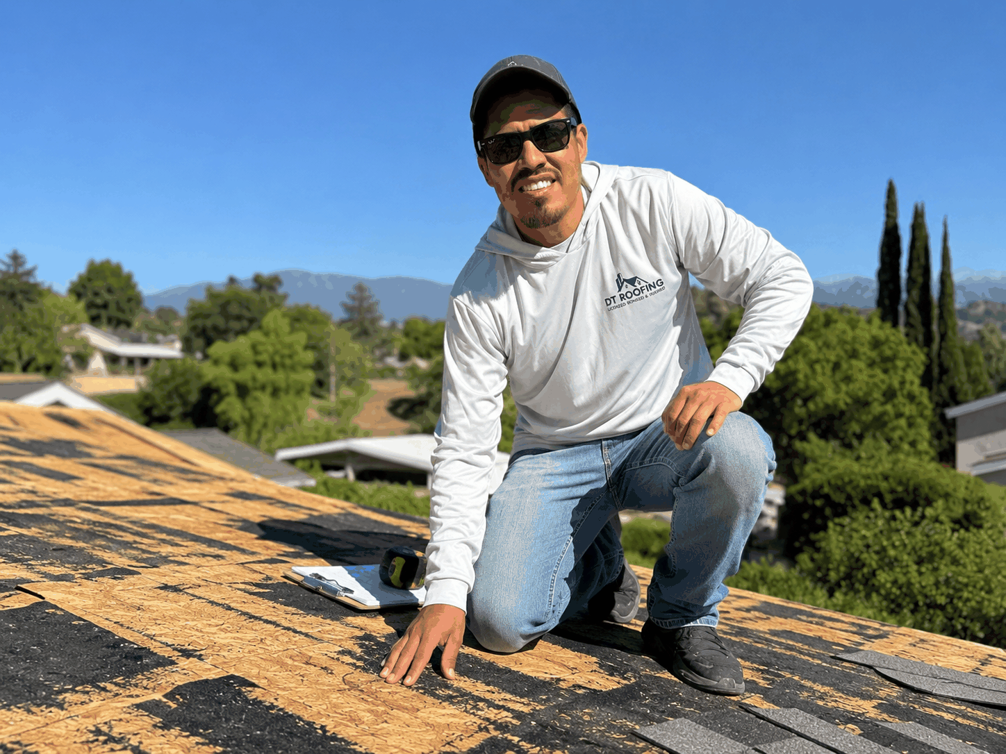 DT Roofing crew on a Spanish-tile rooftop overlooking the Los Angeles skyline at sunset